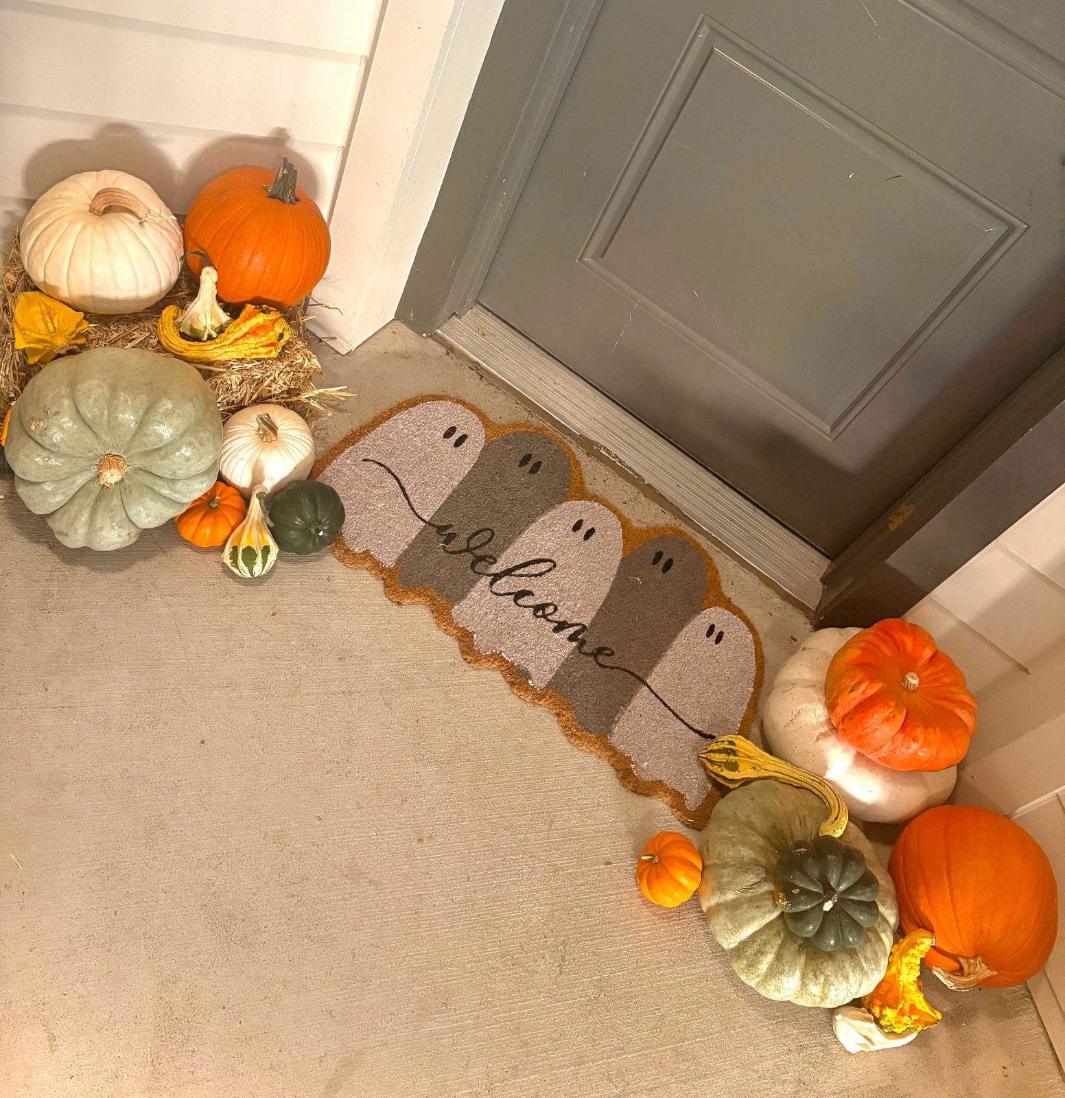 Overhead detail of heirloom and white pumpkins arranged around a doormat
